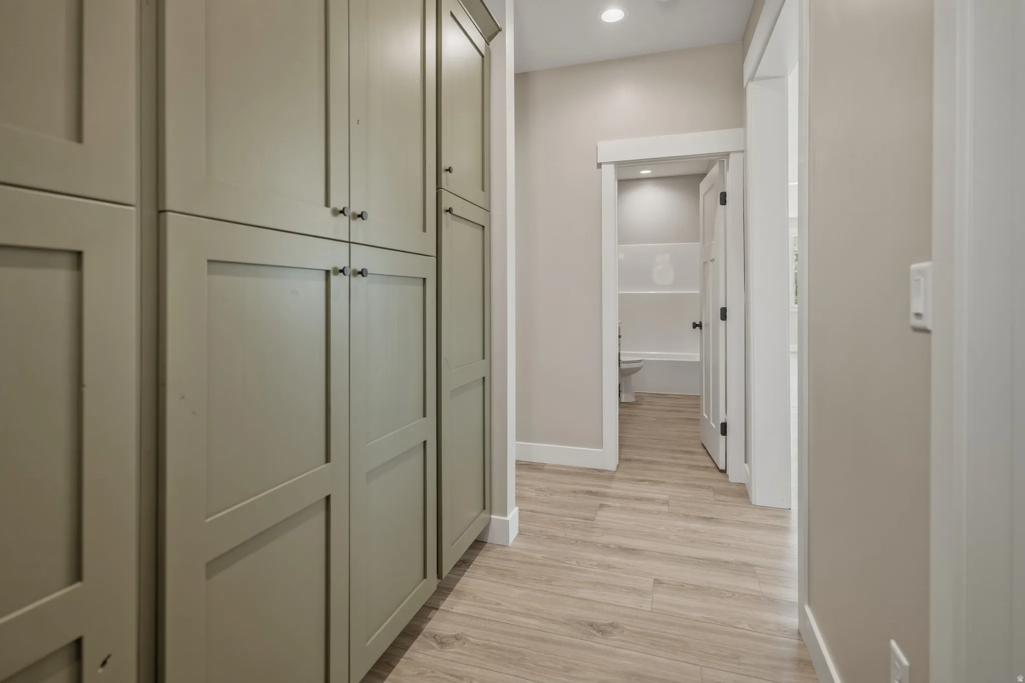 Hallway with light wood finished floors and recessed lighting