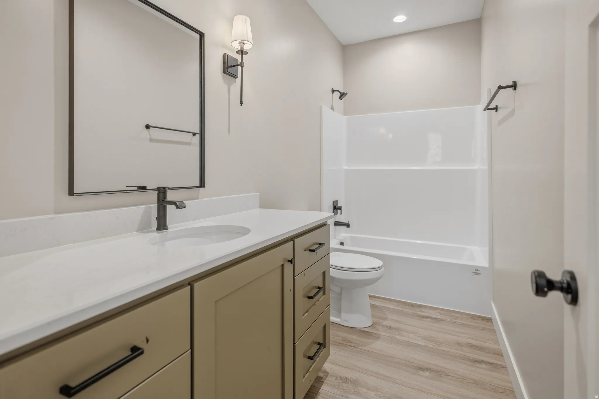 Bathroom featuring vanity, light wood-style floors,  shower combination, and recessed lighting