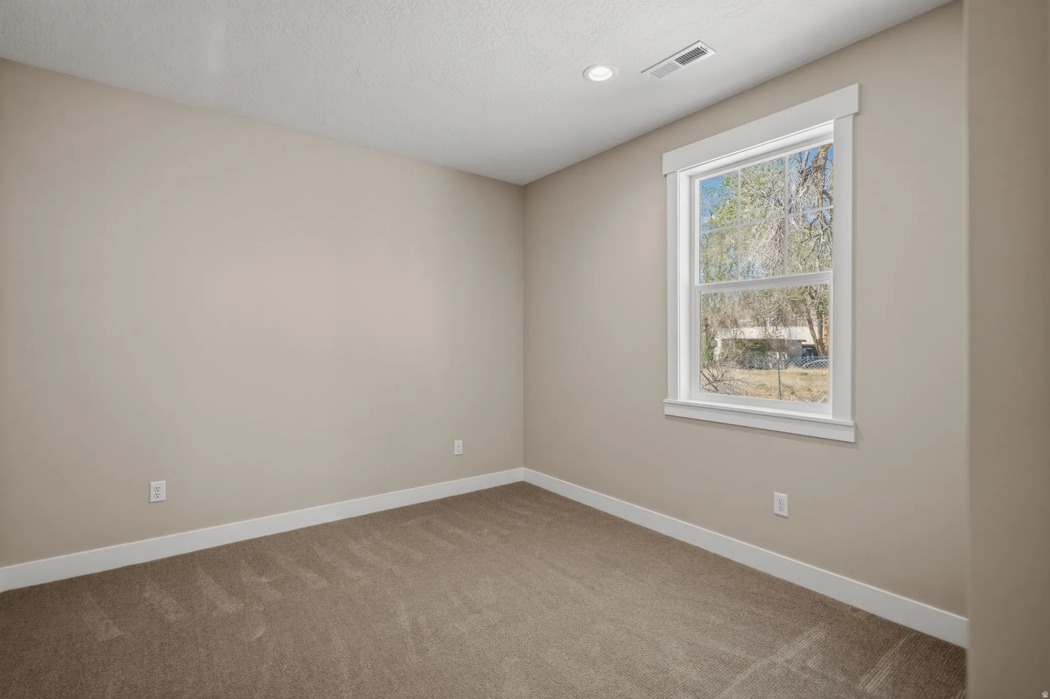 Empty room with light carpet and recessed lighting