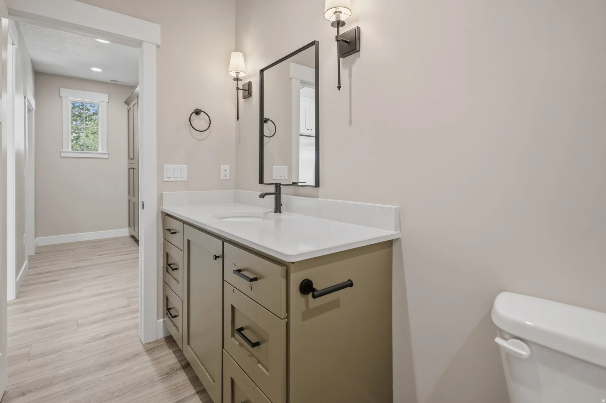 Half bathroom with vanity, light wood finished floors, and recessed lighting