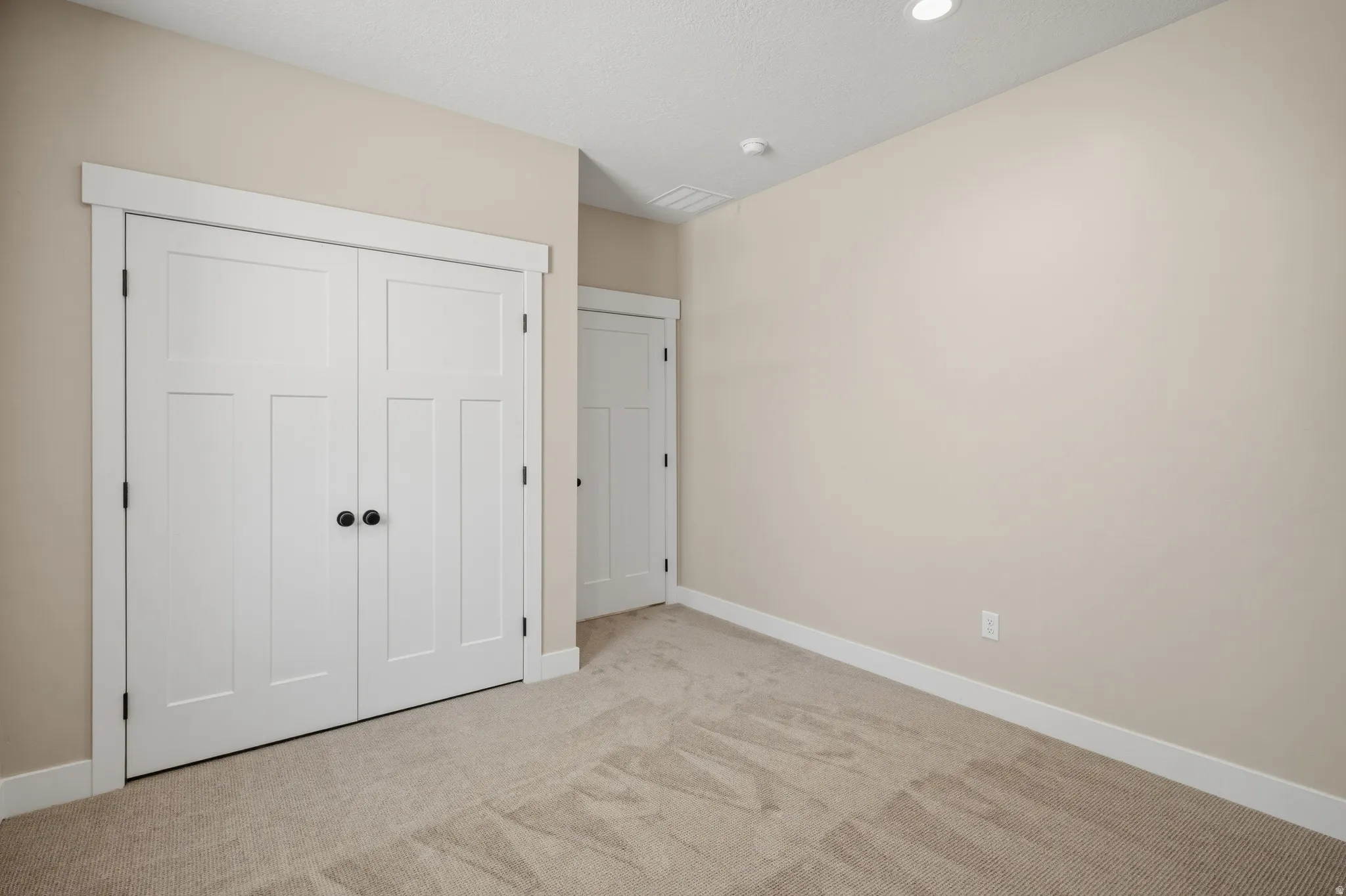 Unfurnished bedroom featuring light carpet, a closet, and recessed lighting