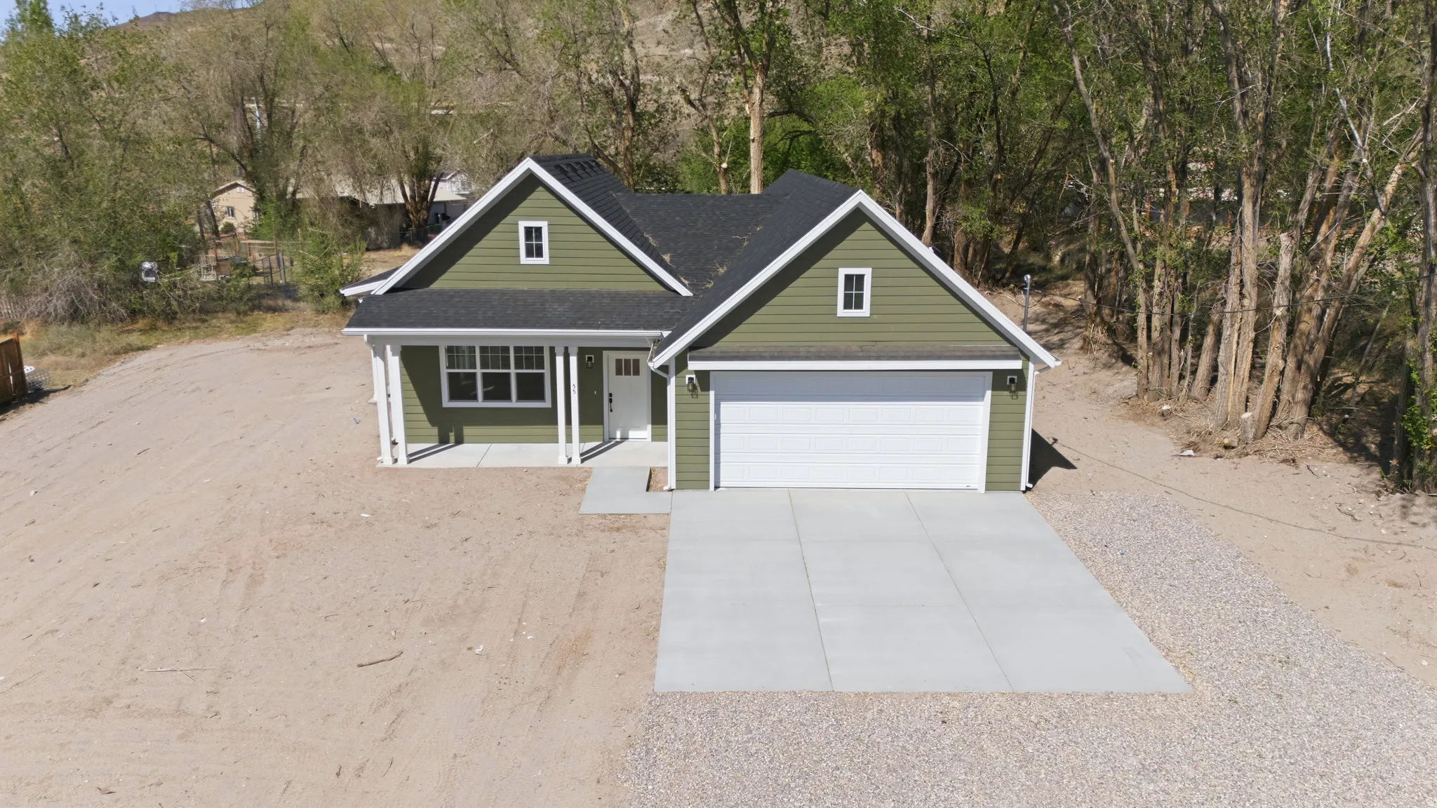 View of front of home featuring concrete driveway, a porch, a shingled roof, an attached garage, and view of scattered trees