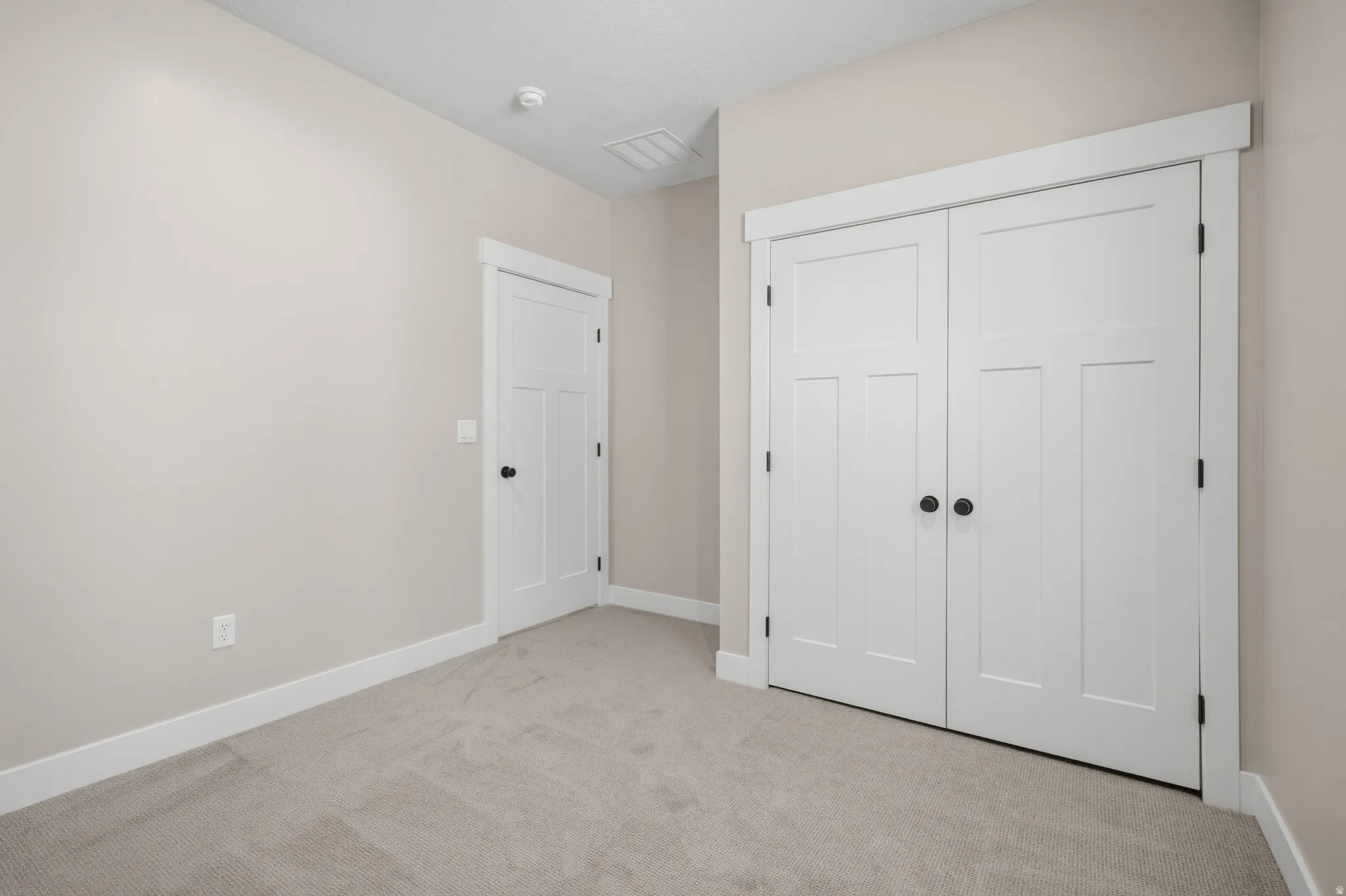 Unfurnished bedroom with light carpet and a closet