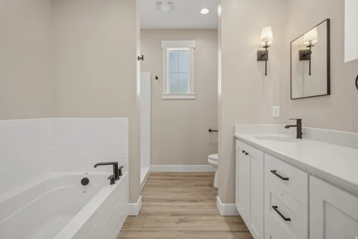 Bathroom featuring vanity, a garden tub, light wood-style floors, and recessed lighting