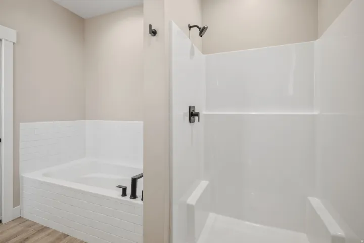Bathroom with a bath, a walk in shower, and light wood-style floors
