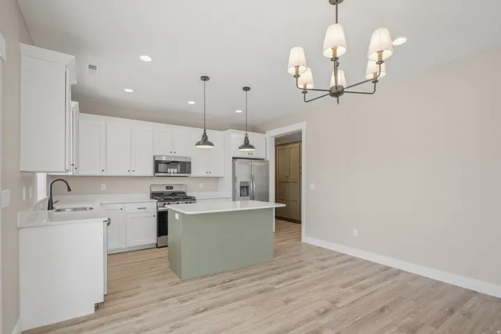 Two tone kitchen featuring stainless steel appliances, a center island, light wood-type flooring, a chandelier, and dual tone cabinets