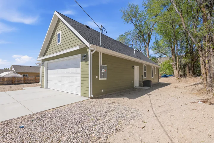 View of side of home featuring driveway and roof with shingles