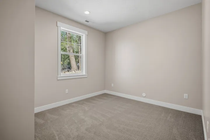 Unfurnished room featuring light carpet and baseboards