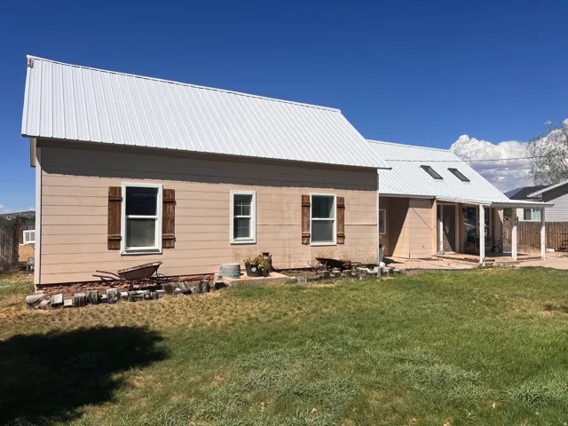 Metal roof with skylights, horizontal siding, wood shutters, and covered patio