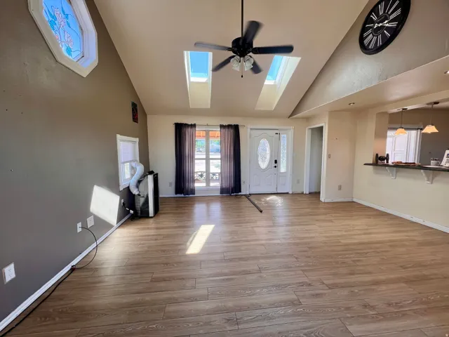 Vaulted ceiling with skylights, wood-finish flooring, ceiling fan, and a breakfast bar with pendant lighting