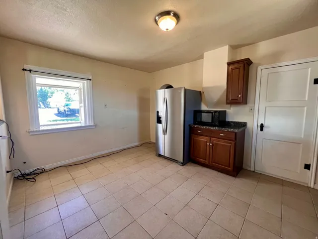 Tile flooring with a matte finish, built-in cabinetry with a dark wood finish, and a granite-style countertop