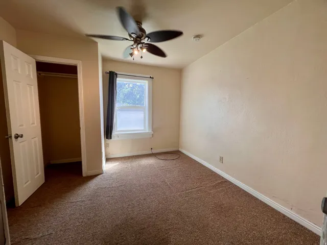 Recessed closet, ceiling fan with integrated lighting, window with frosted lower pane, and wall-to-wall carpeting