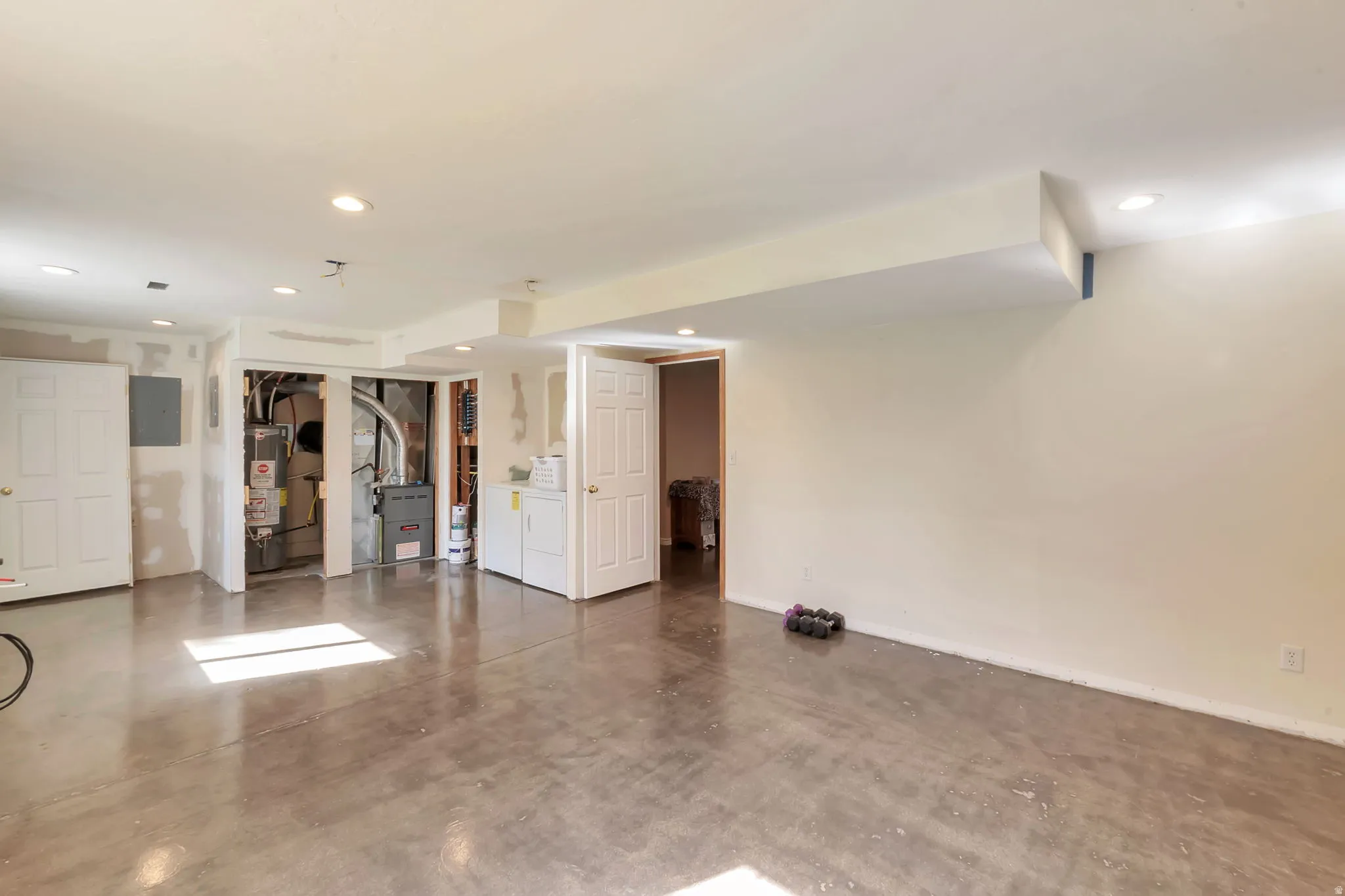 Finished basement featuring heating unit, gas water heater, recessed lighting, and electric panel