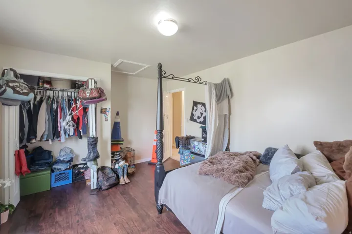 Bedroom with dark wood-style flooring and a closet