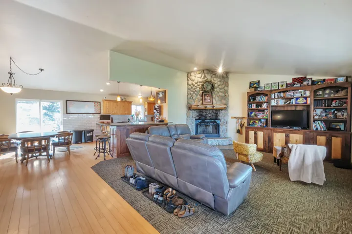 Living area with a stone fireplace, vaulted ceiling, and light wood-type flooring