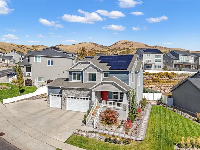 View of front facade with solar panels, a residential view, concrete driveway, and a mountain view