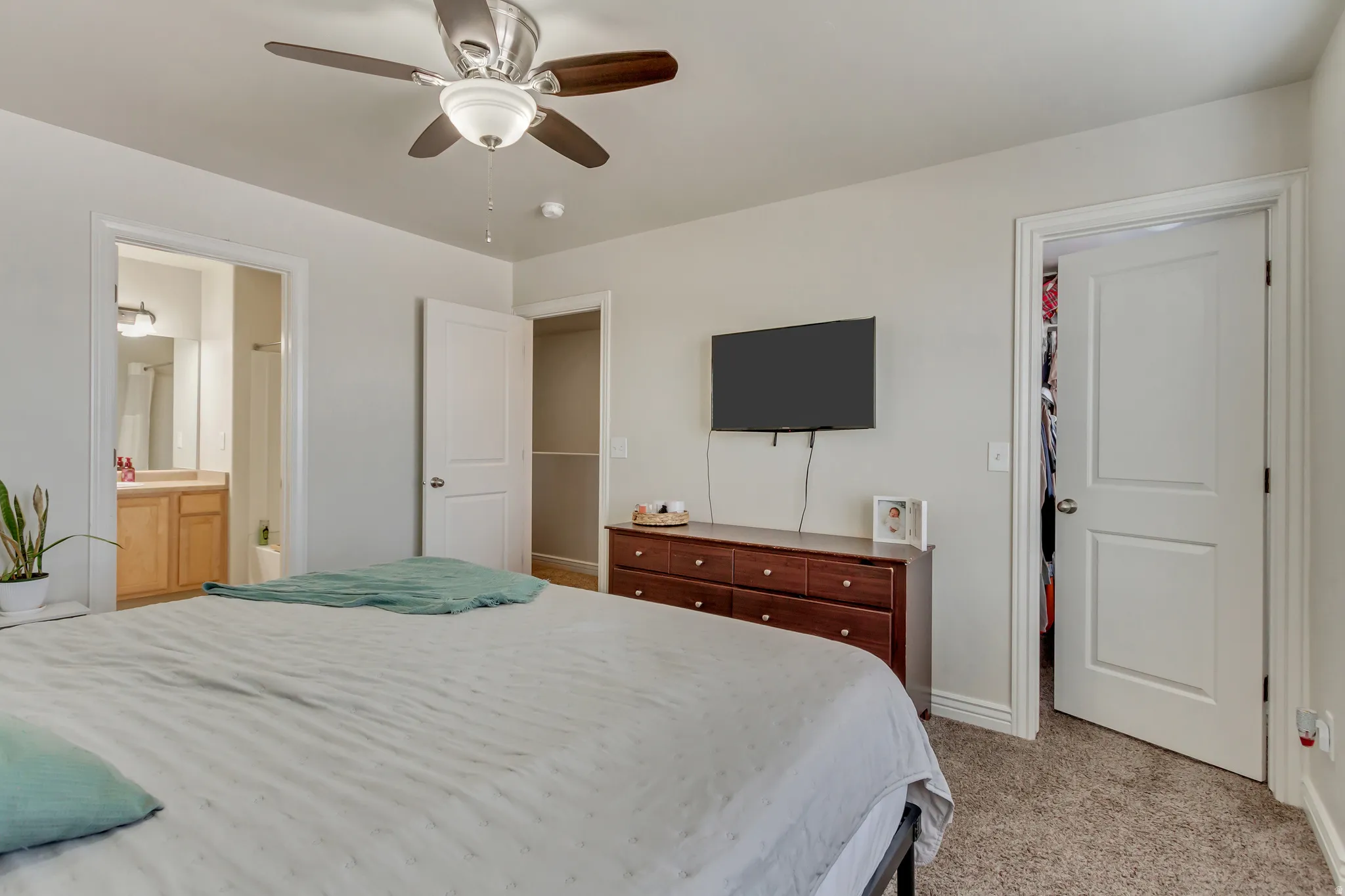 Bedroom featuring light colored carpet, a ceiling fan, and ensuite bathroom