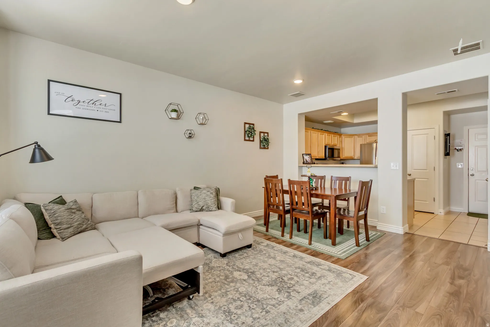 Living room featuring light wood-type flooring, a tray ceiling, and recessed lighting
