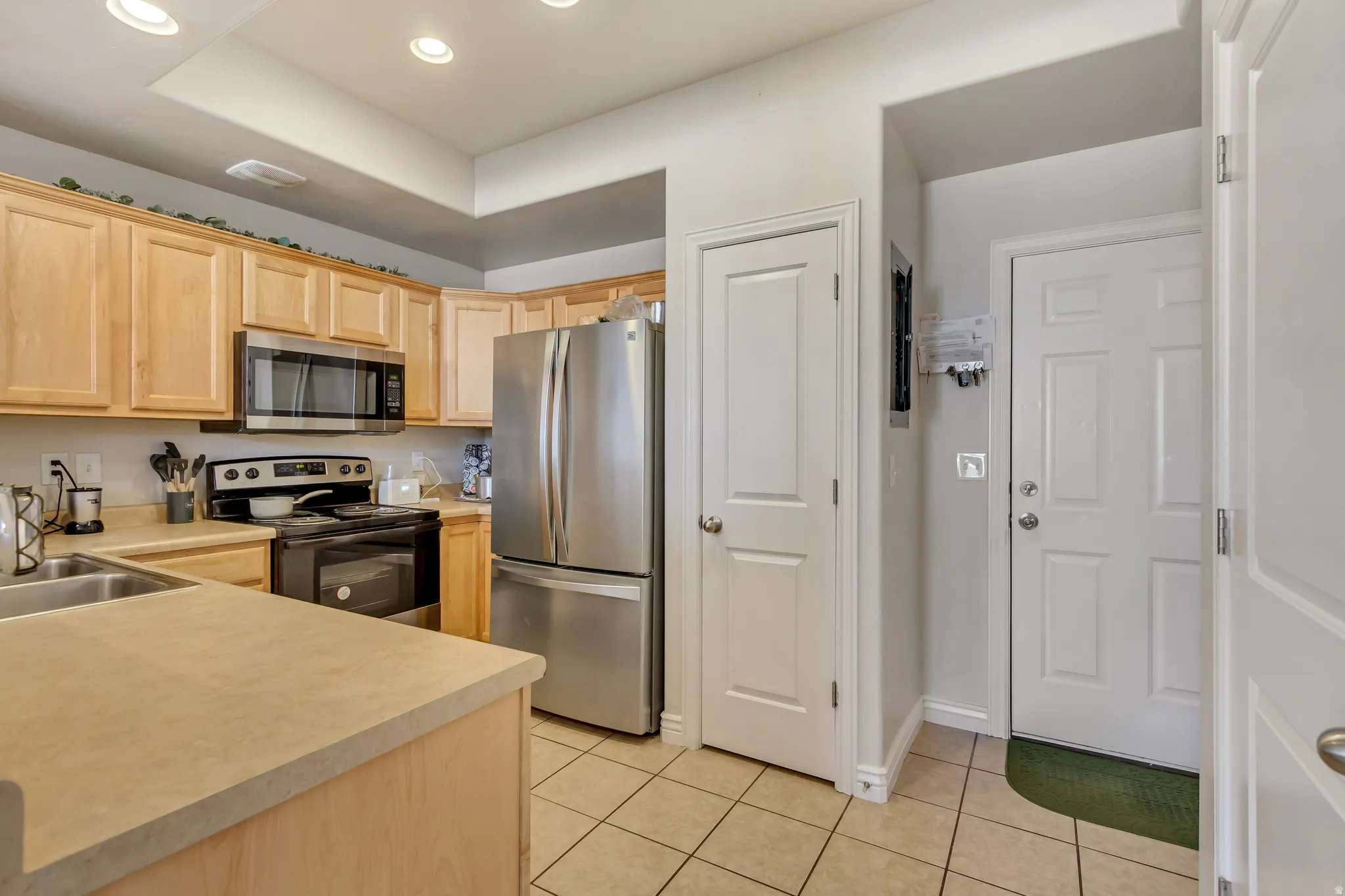 Kitchen featuring light wood finish cabinets, stainless steel appliances, light countertops, light tile patterned floors, and recessed lighting