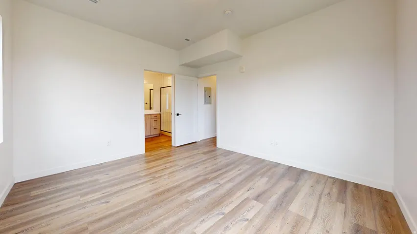 Unfurnished bedroom featuring light wood finished floors and ensuite bathroom