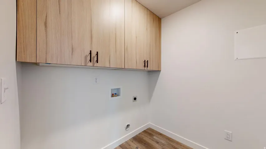 Laundry area featuring light wood-style flooring, washer hookup, cabinet space, and hookup for an electric dryer