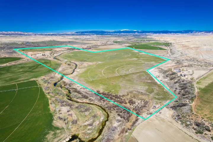 Aerial view of sparsely populated area featuring a mountain backdrop and property parcel outlined