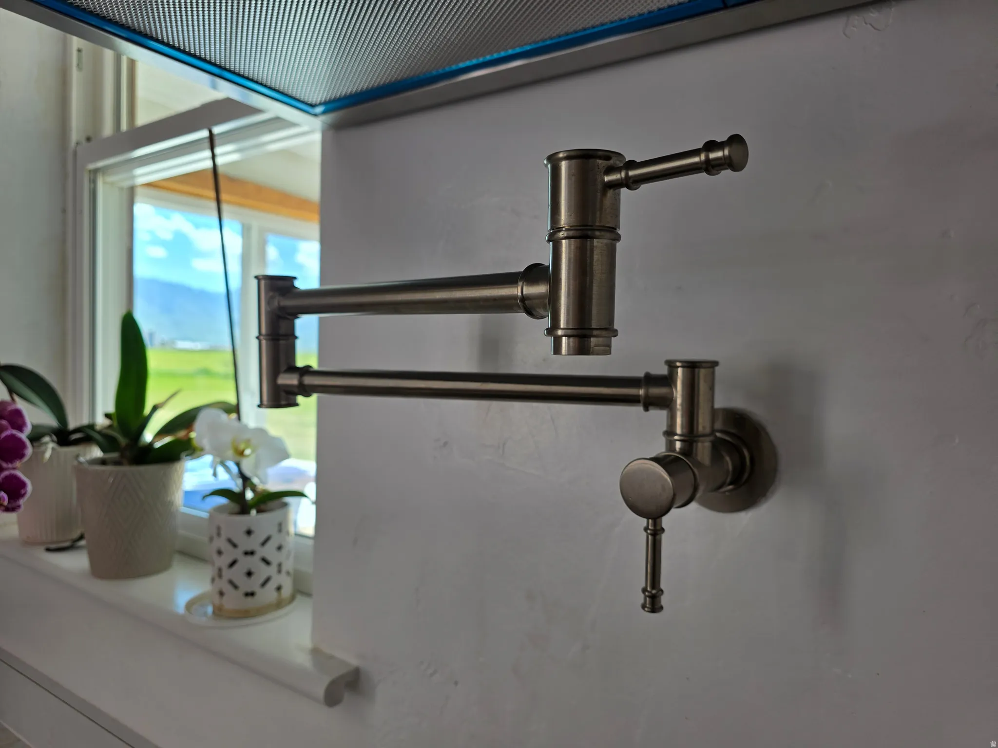 Wall-mounted pot filler with a brushed metal finish