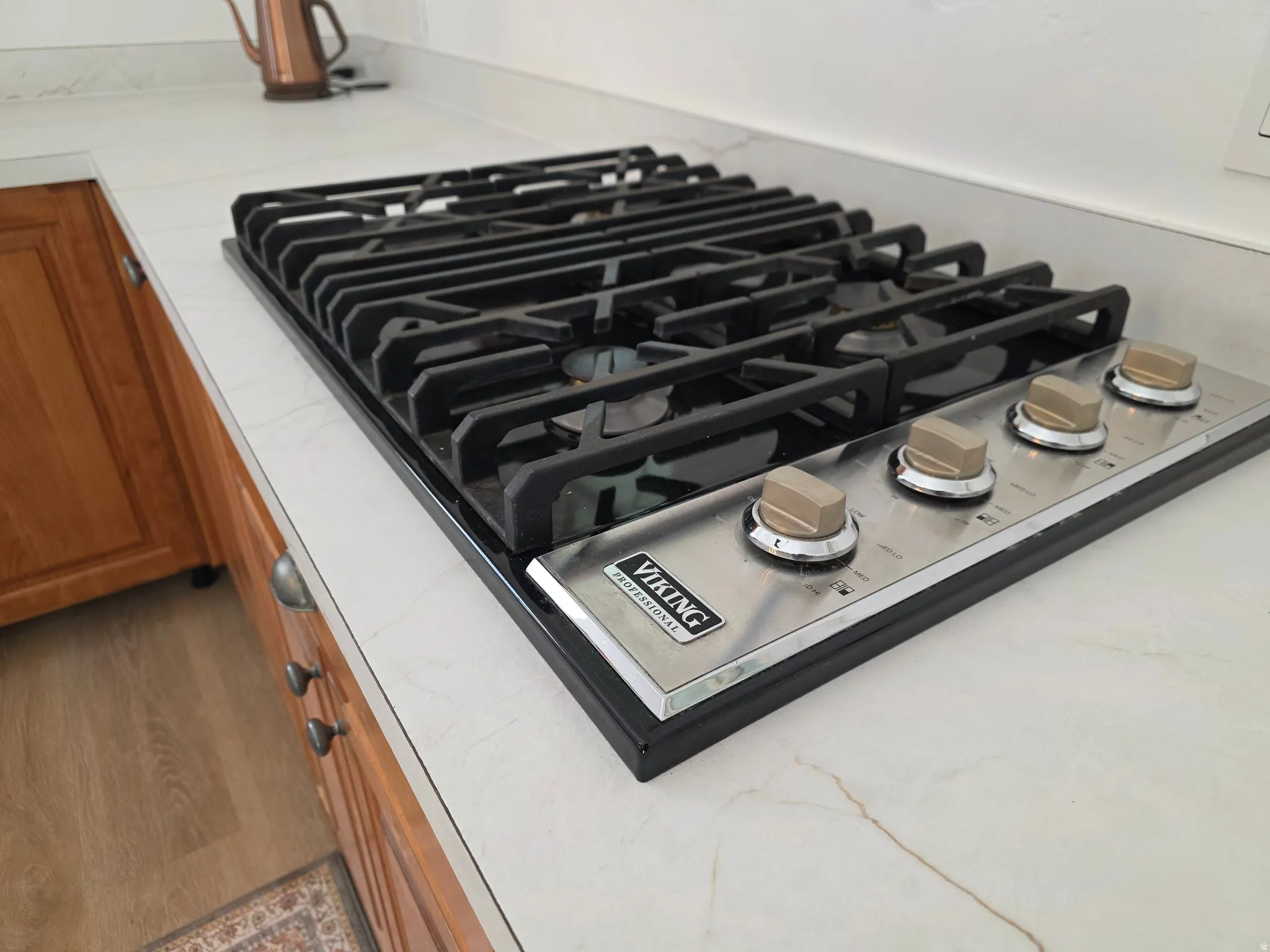 Kitchen view of stainless steel gas stovetop and wood finish cabinetry