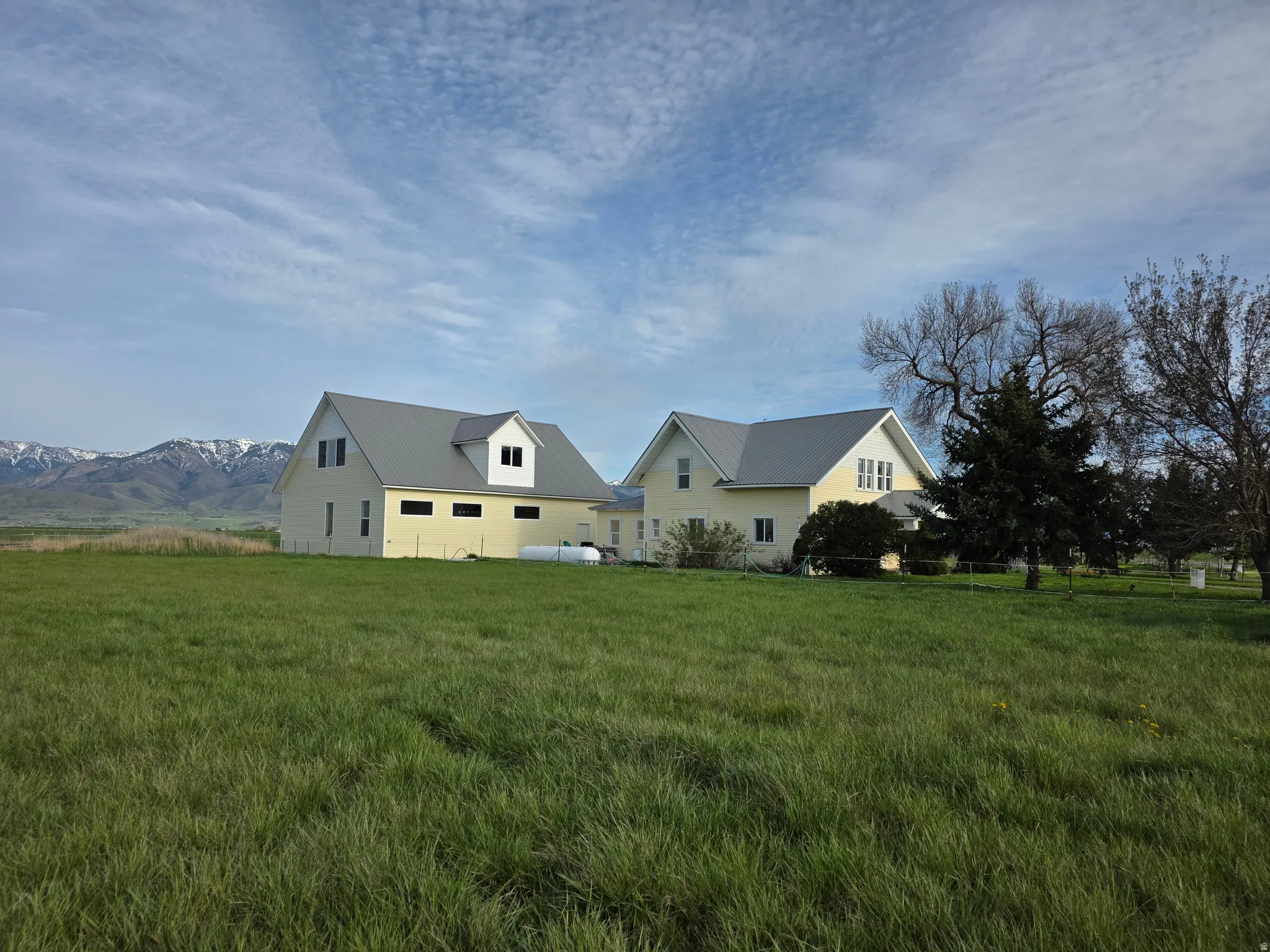 View of front facade featuring a front lawn, a metal roof, and a mountain view