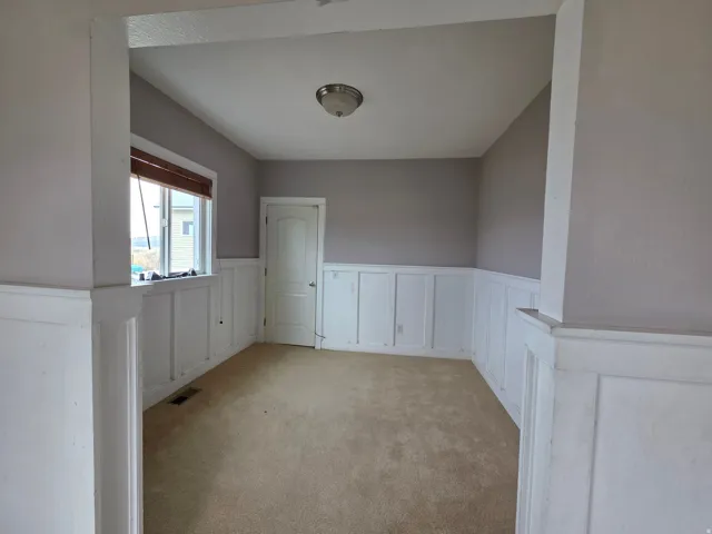 Spare room featuring a wainscoted wall, a decorative wall, and carpet flooring