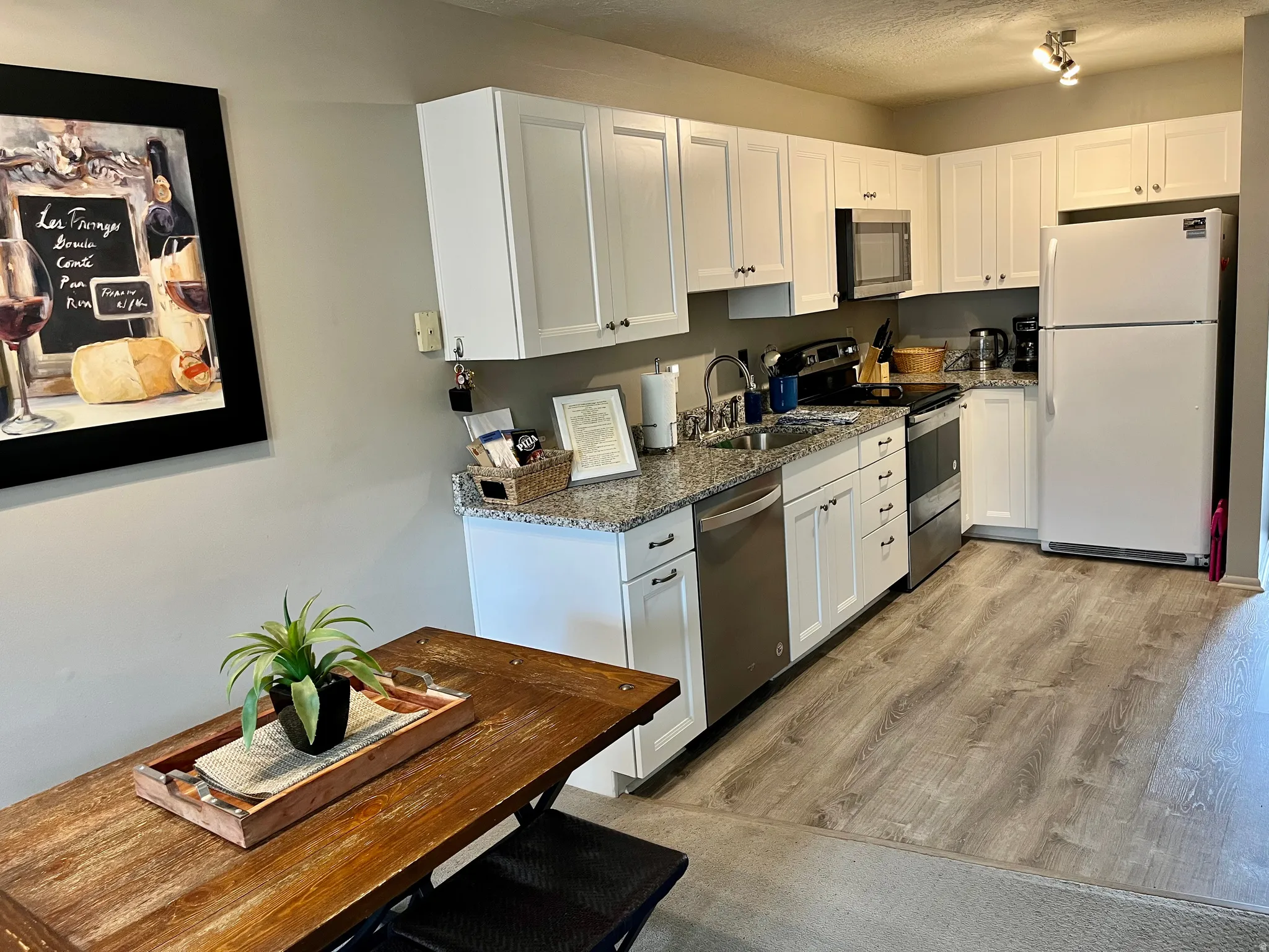 Remodeled Kitchen featuring stainless steel appliances, white cabinets, dark stone countertops, light wood-style flooring