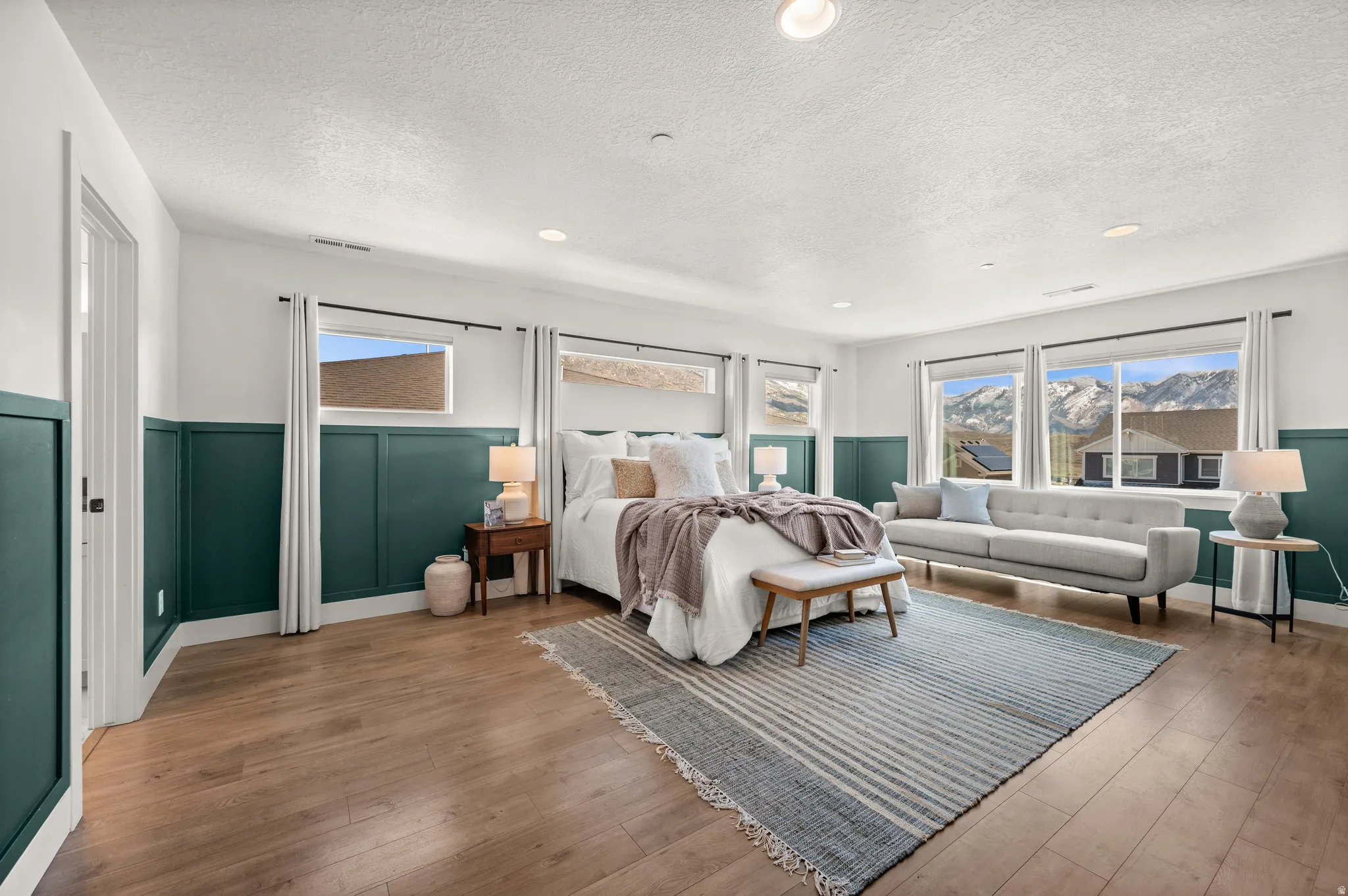 Bedroom with a wainscoted wall, hardwood / wood-style floors, a decorative wall, recessed lighting, and a textured ceiling