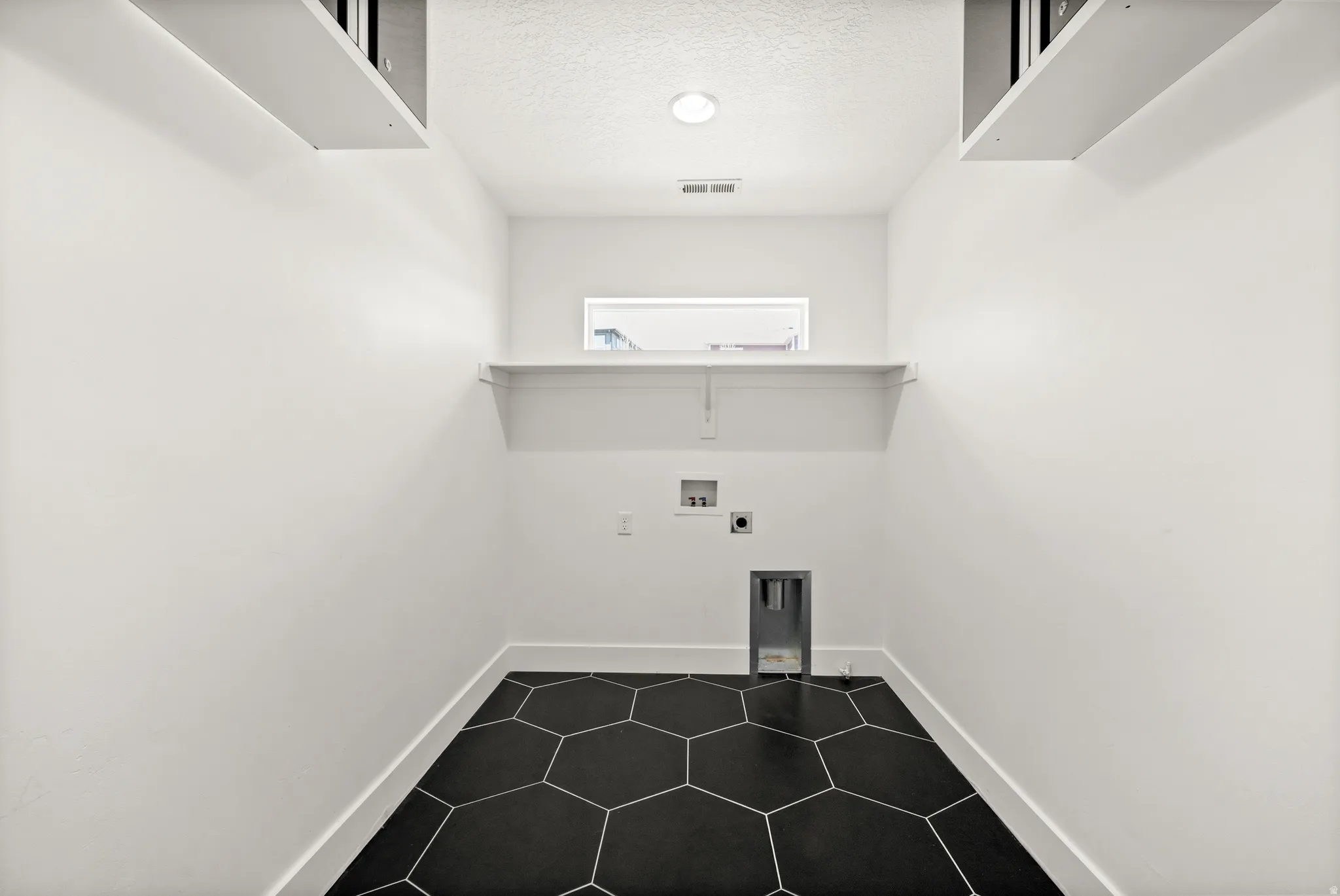 Laundry area with washer hookup, a textured ceiling, electric dryer hookup, and dark tile patterned floors