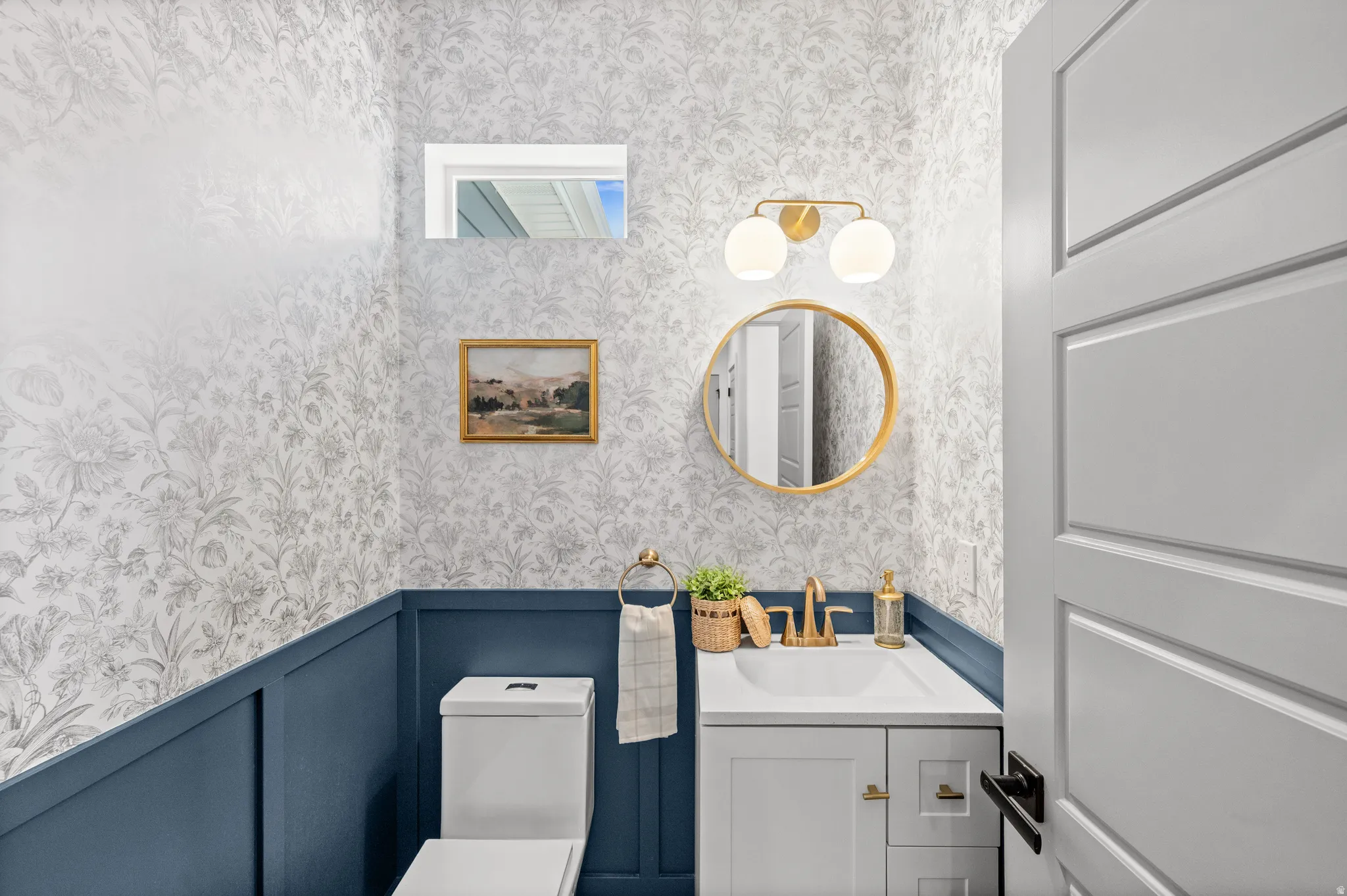 Half bath with vanity and wallpapered walls
