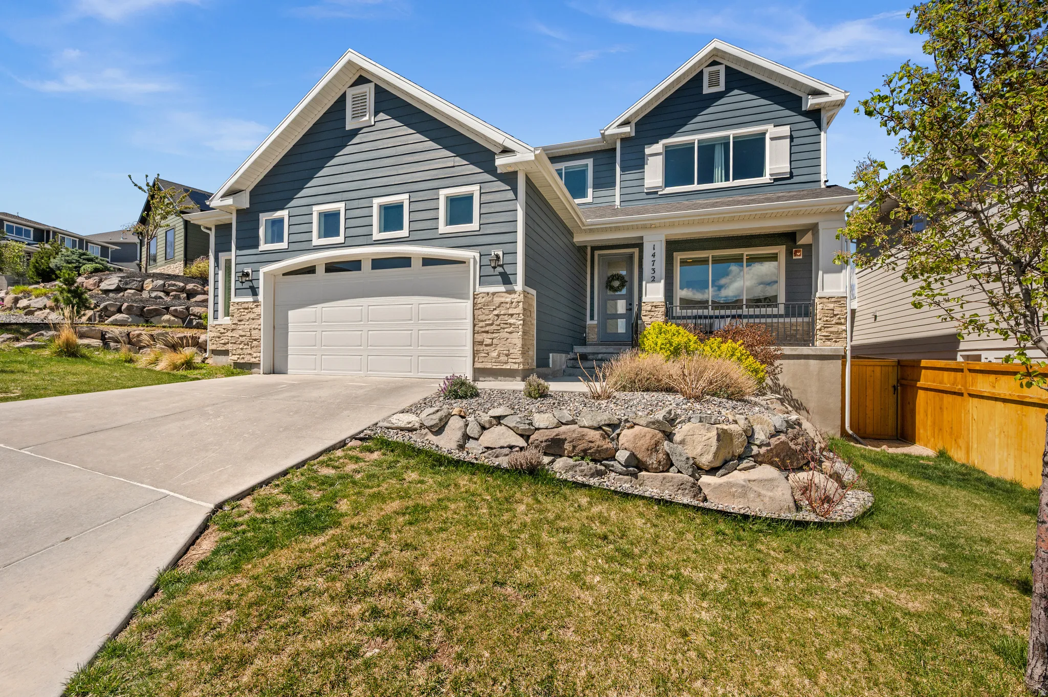 Craftsman-style house featuring a porch, stone siding, driveway, and an attached garage