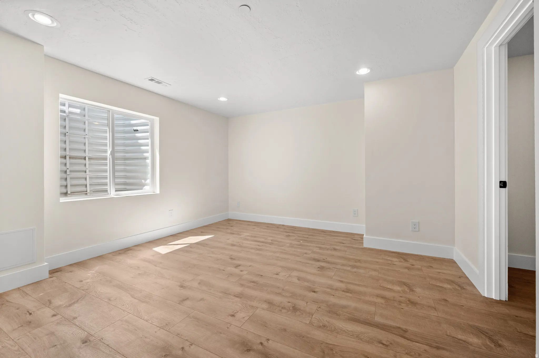 Empty room featuring light wood-style floors and recessed lighting