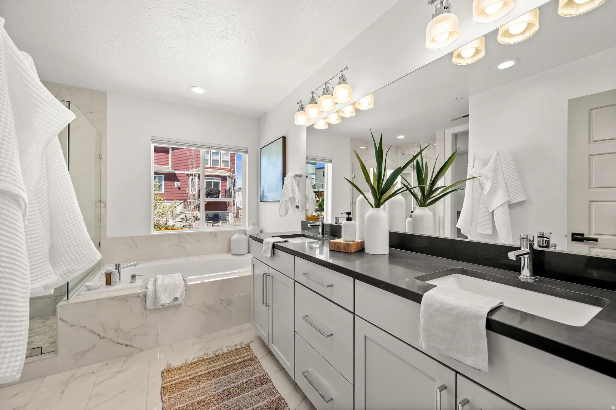 Bathroom featuring double vanity, a marble finish shower, a bath, and recessed lighting
