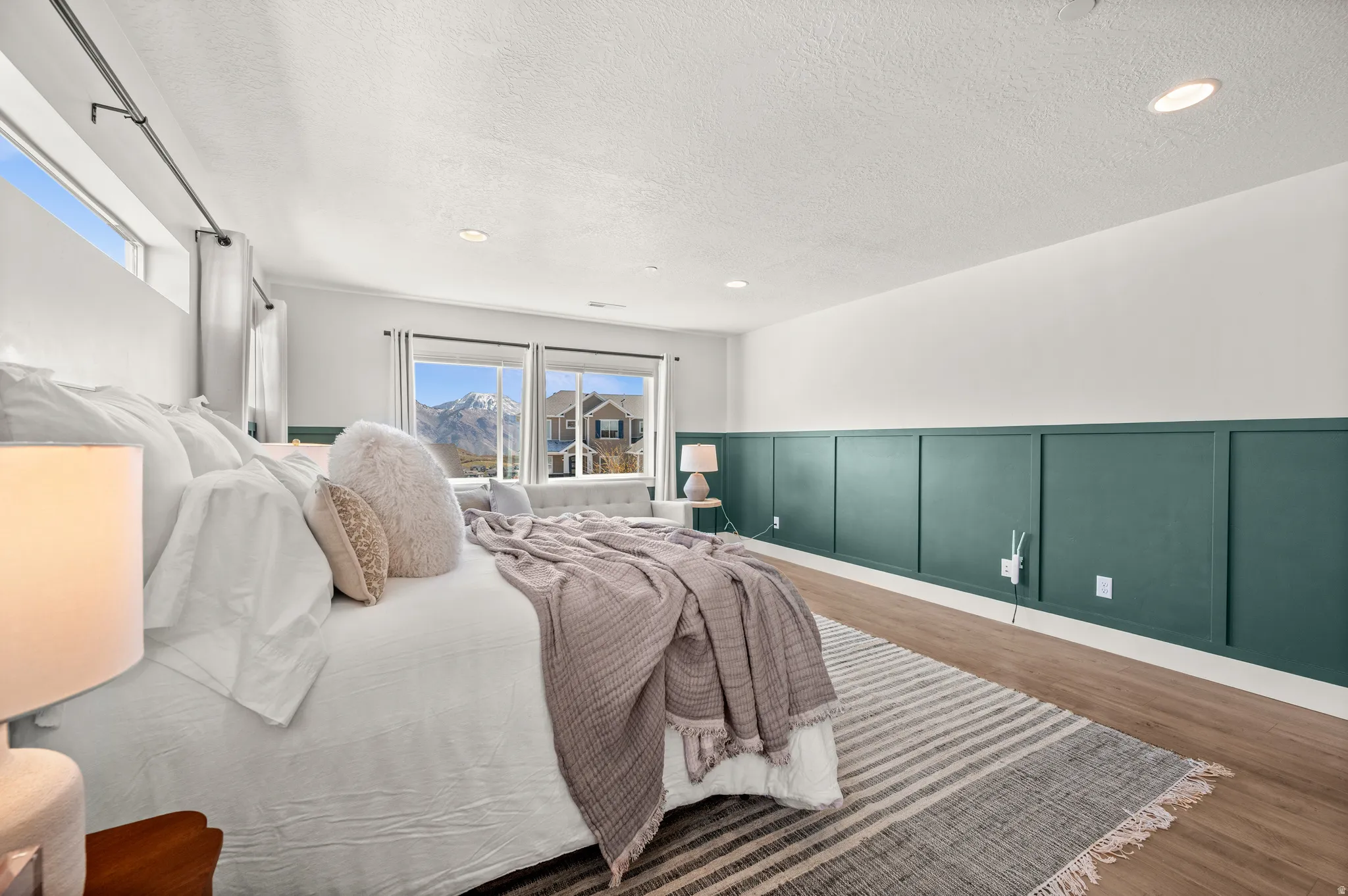 Bedroom featuring a wainscoted wall, dark wood finished floors, a decorative wall, recessed lighting, and a textured ceiling