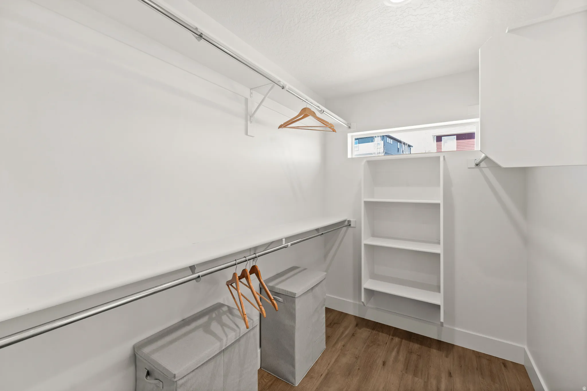 Walk in closet with light wood finished floors