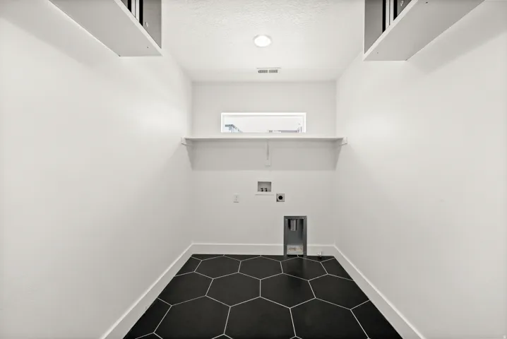 Laundry area with washer hookup, a textured ceiling, electric dryer hookup, and dark tile patterned floors