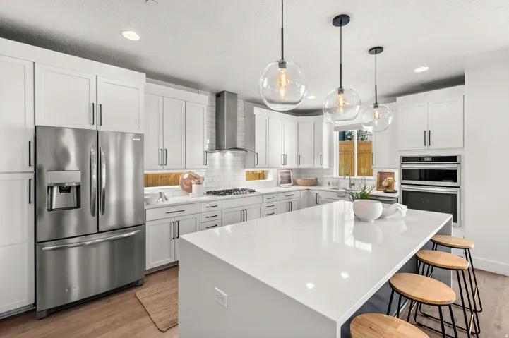 Kitchen featuring stainless steel appliances, white cabinetry, a center island, light stone countertops, and light wood-style floors