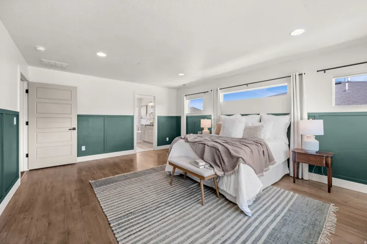 Bedroom featuring recessed lighting, wainscoting, wood finished floors, and connected bathroom