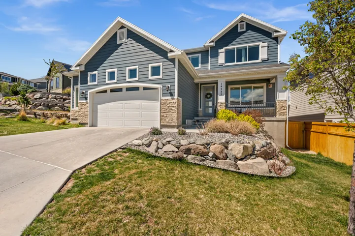 Craftsman-style house featuring a porch, stone siding, driveway, and an attached garage