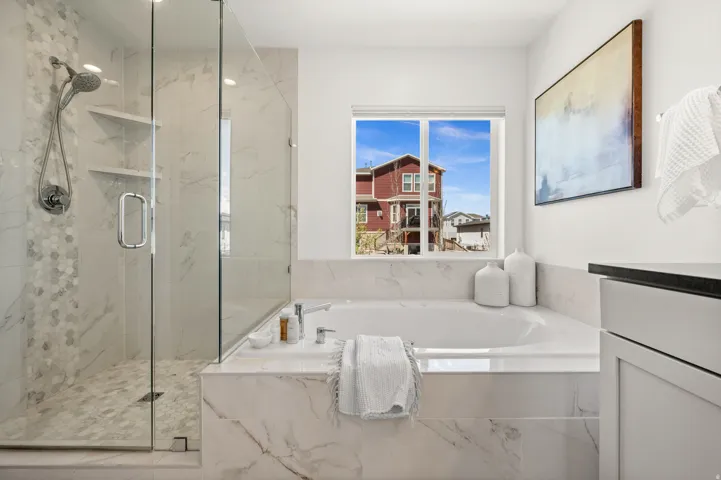 Full bath featuring a marble finish shower, a garden tub, and vanity