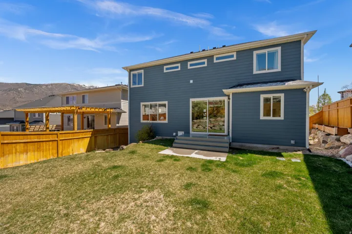 Rear view of house with a fenced backyard, a mountain view, entry steps, and a patio