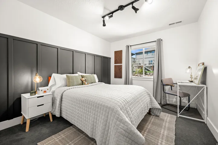 Bedroom with a decorative wall, dark colored carpet, rail lighting, a textured ceiling, and ceiling fan