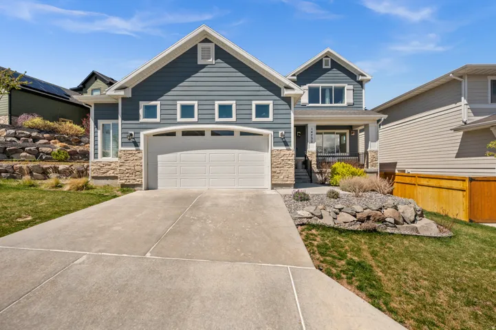 Craftsman inspired home with stone siding, driveway, a front lawn, and covered porch