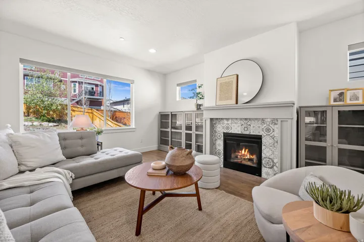 Living area with a tiled fireplace, wood finished floors, recessed lighting, and a textured ceiling