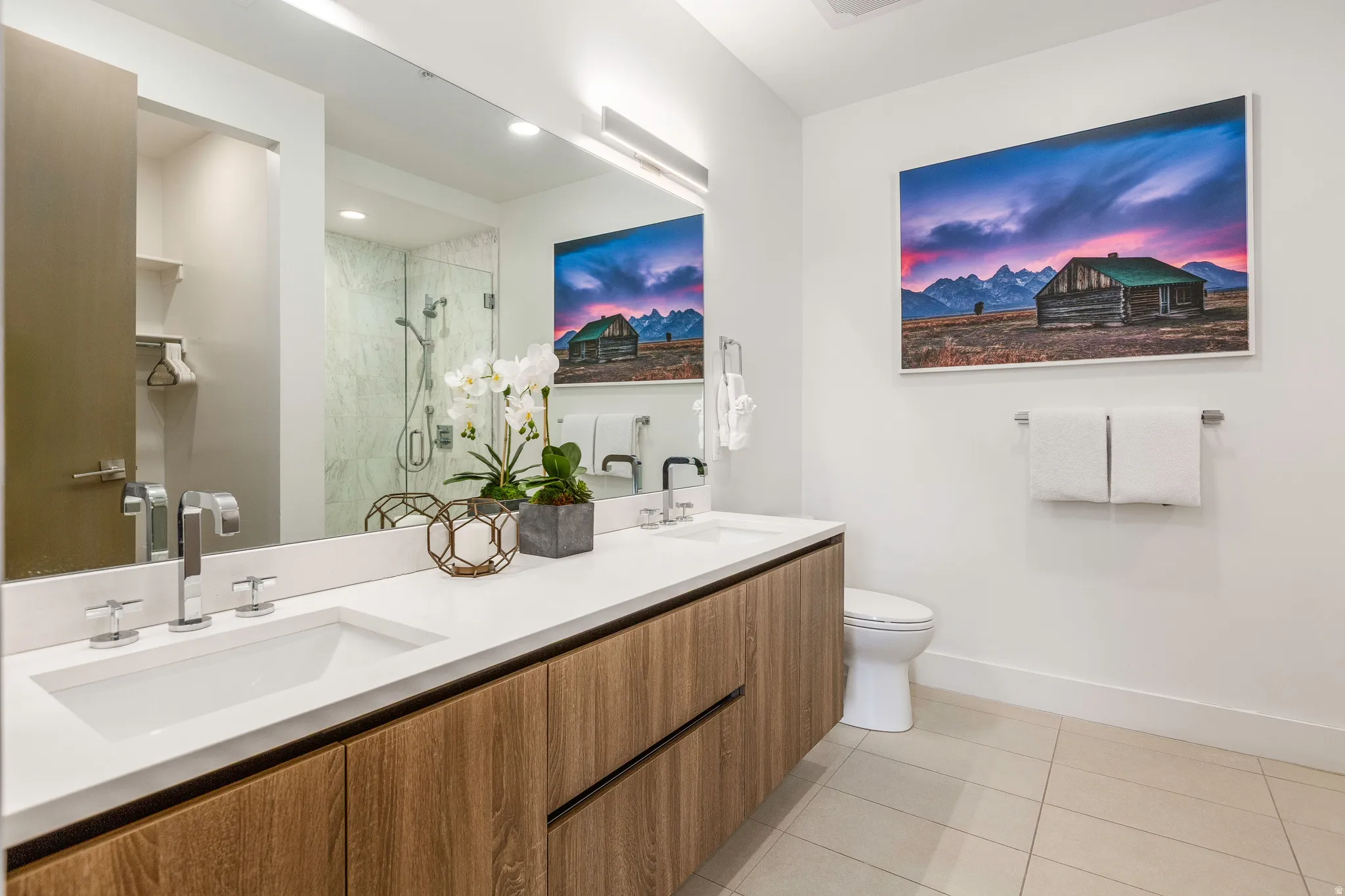 Bathroom featuring a stall shower, double vanity, and light tile patterned flooring