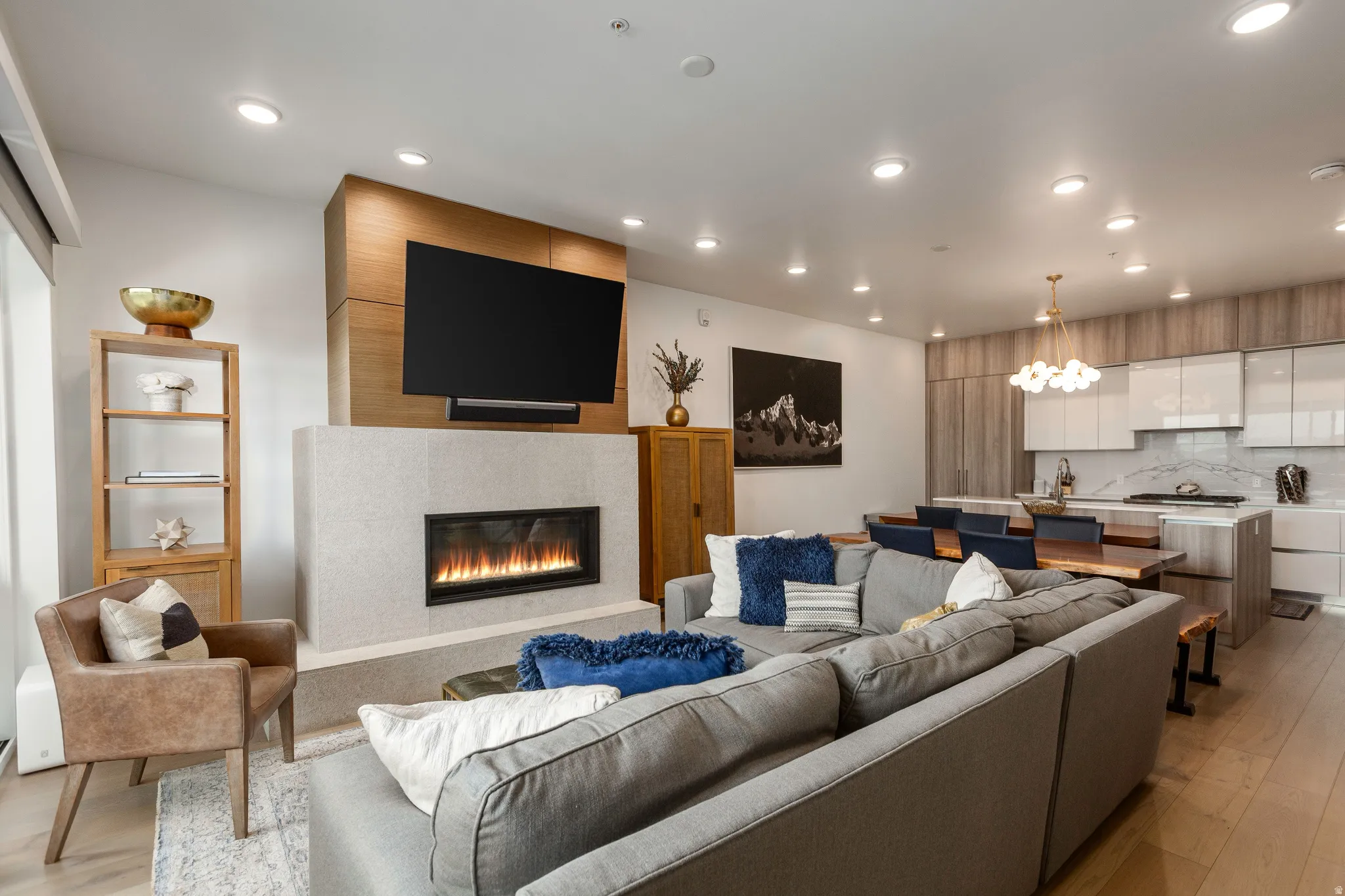Living room with light wood-style flooring, a tile fireplace, and suspended lighting